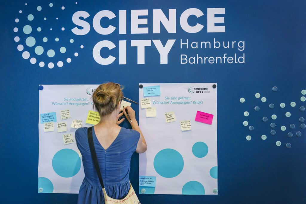 Foto von einer Frau, die eine Idee für die Science City auf einen Notizzettel schreibt.