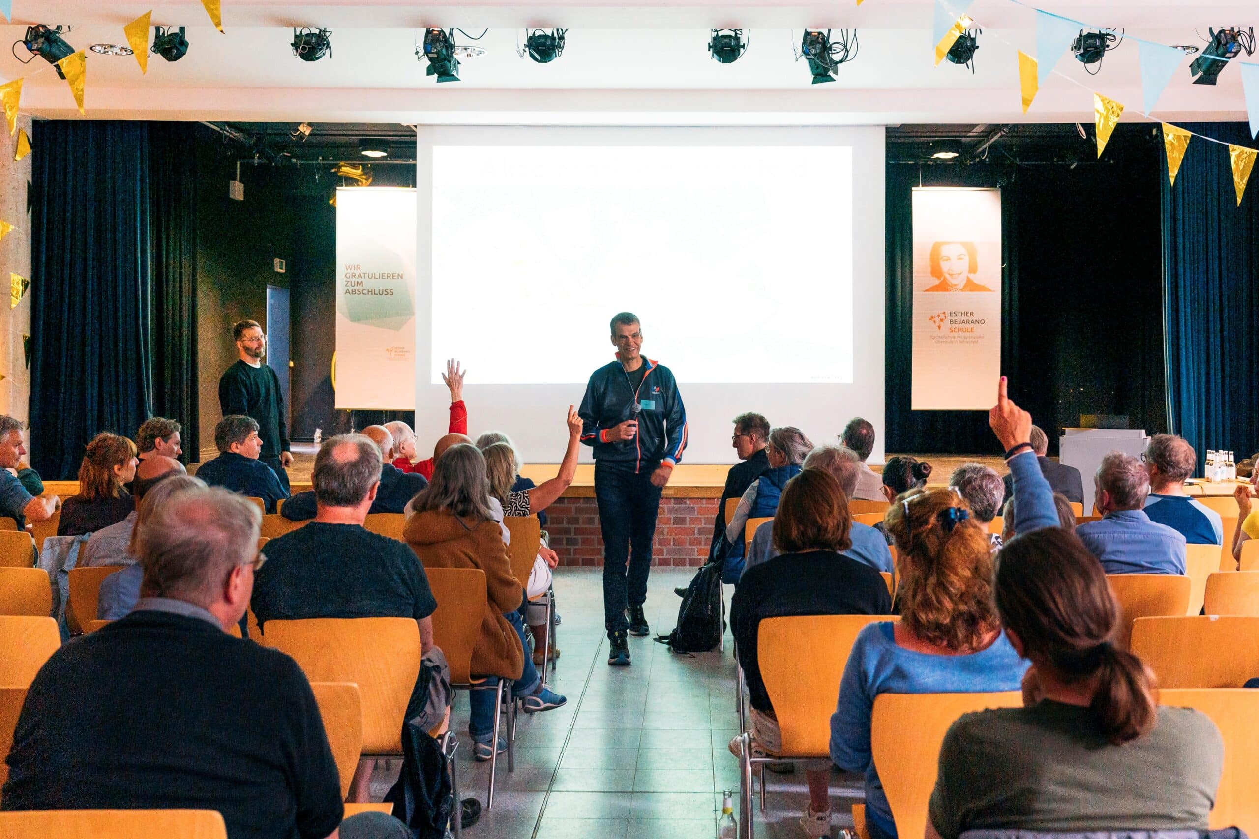 Ein Mann hält eine Präsentation vor einer Gruppe von Zuhörern in einem Konferenzraum.