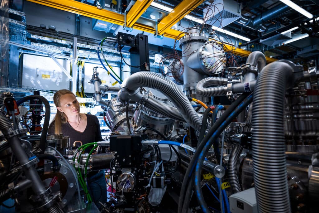 Foto einer Forscherin, die den technischen Aufbau eines Experiments prüft